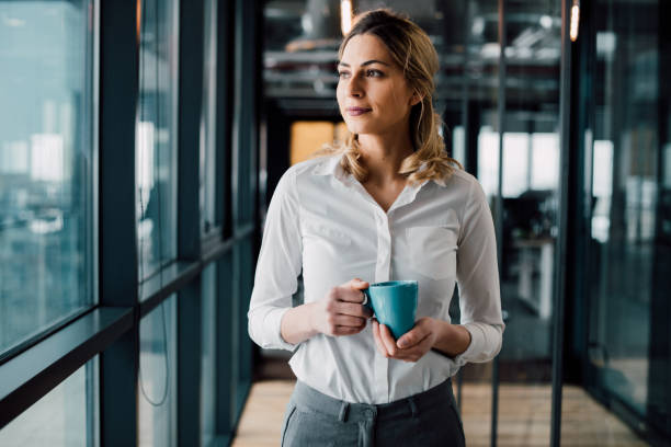 Thoughtful businesswoman looking away Thoughtful businesswoman looking away with cup of coffee looking away stock pictures, royalty-free photos & images