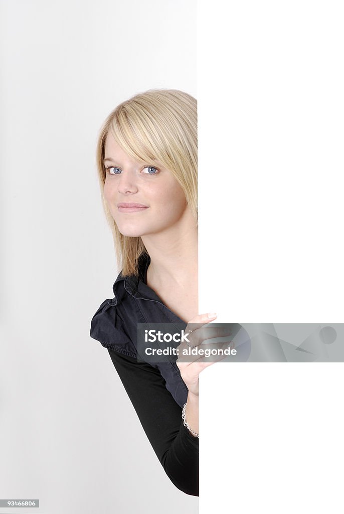 Linda loira com olhos azuis em busca de trás de uma propaganda - Foto de stock de Adolescente royalty-free