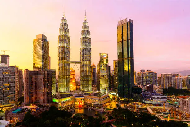 Photo of The Kuala Lumpur City Skyline With the Petronas Towers Illuminated at Sunset, Malaysia.