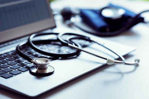 Stethoscope on laptop keyboard in doctor surgery Stethoscope on laptop keyboard in doctor surgery with blood pressure monitor debug stock pictures, royalty-free photos & images