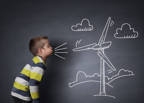 Child blowing a chalk wind turbine Child blowing a chalk drawing of a wind turbine on a blackboard concept for alternative renewable energy and education of the environment wind power photos stock pictures, royalty-free photos & images
