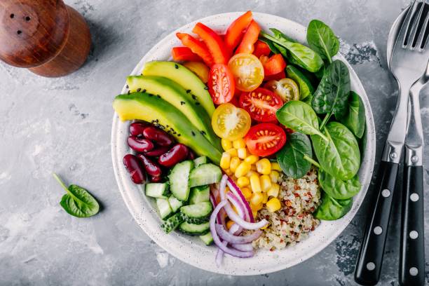 Healthy vegan lunch Buddha bowl. Avocado, quinoa, tomato, cucumber, red beans, spinach, red onion and red paprika vegetables salad. Healthy vegan lunch Buddha bowl. Avocado, quinoa, tomato, cucumber, red beans, spinach, red onion and red paprika vegetables salad. Top view salad bowl stock pictures, royalty-free photos & images