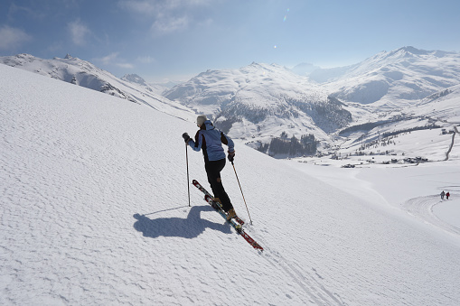 Female ski mountaineer ascends mountain slope.