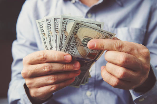 istock hands counting dollar banknotes on dark wooden surface 934690804
