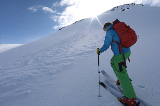 istock Ski mountaineer ascends slope towards mountain summit and sun. 934691002