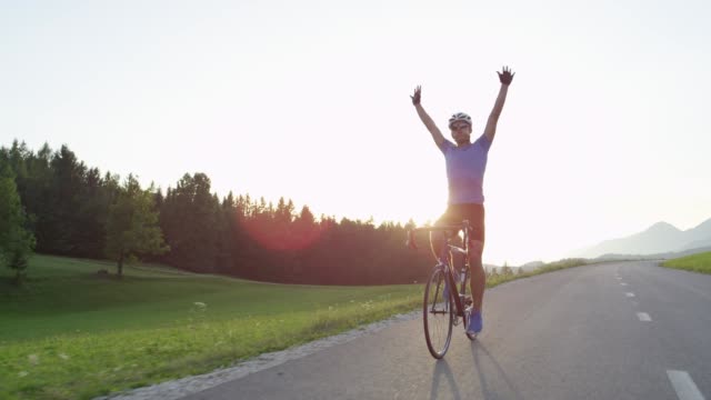 SLOW MOTION: Road biker happy to finish challenging race in golden-lit nature.