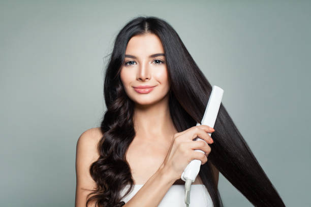 aantrekkelijke vrouw met krullend haar en lange rechte haren met hair straightener. haar probleem en haarverzorging concept - bijstellen fotos stockfoto's en -beelden