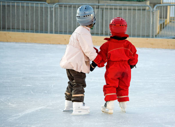 Two young girls with protective helmets skating.
