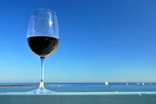 Glass of red wine on a restaurant's deck railing by the ocean beach