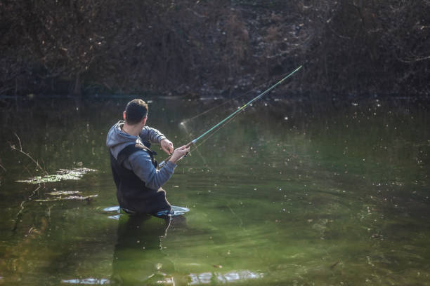 istock Fisherman standing in water and fighting fish. 934765576