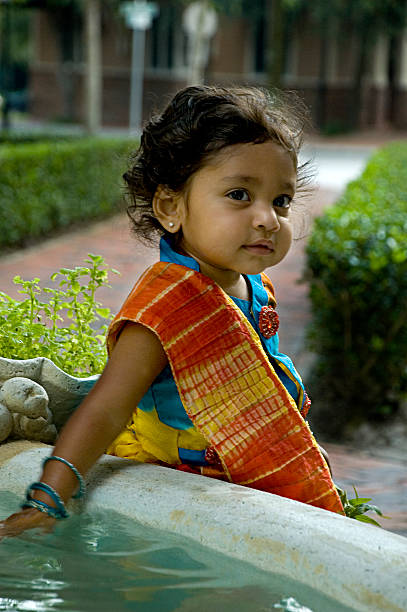 Cute Indian girl child in traditional dress against white wall