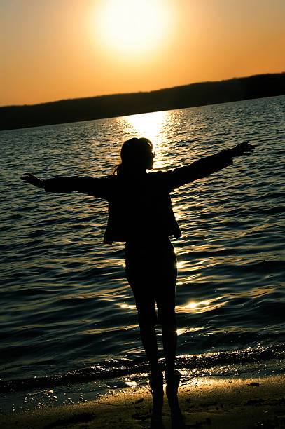 istock girl on a sunset water with arms outspread 93478421