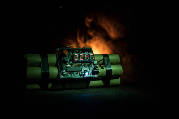 istock Image of a time bomb against dark background. Timer counting down to detonation illuminated in a shaft light shining through the darkness 934798488