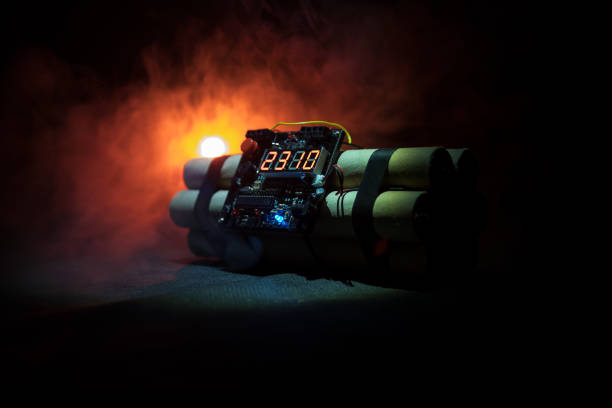 istock Image of a time bomb against dark background. Timer counting down to detonation illuminated in a shaft light shining through the darkness 934798508