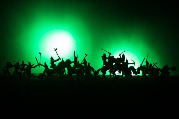 istock Medieval battle scene with cavalry and infantry. Silhouettes of figures as separate objects, fight between warriors on dark toned foggy background. Night scene. 934807252