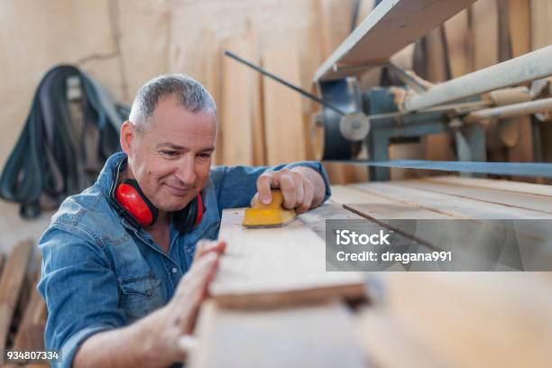 Hardworking Carpenter Polishing Wood Using Abrasive Paper Stock Photo - Download Image Now