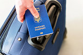 male hand holding a ukrainian passport above his luggage