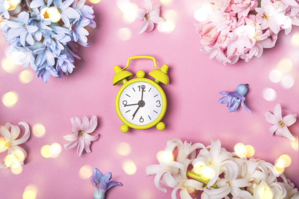 istock Spring flowers pink flat lay. Alarm clock. Springtime concept 934818036