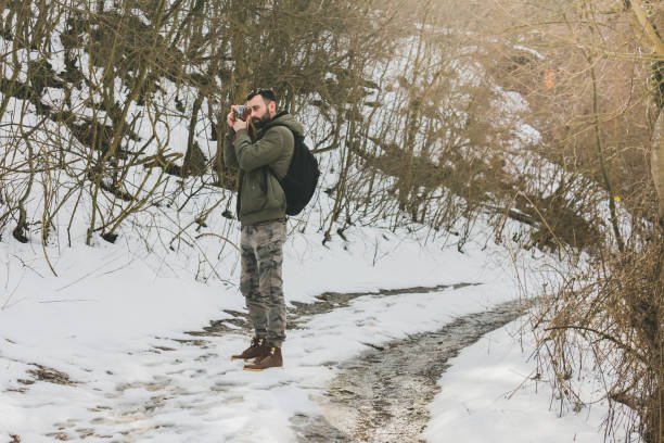 istock Hipster bearded man with retro camera standing in mountains forest background in winter day 934822274
