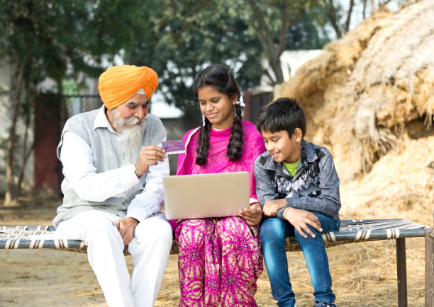 alter mann mit kindern, die mit laptop und kreditkarte - indian culture family senior adult asian ethnicity stock-fotos und bilder
