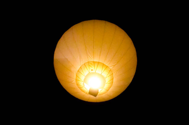 Hot air balloon from beneath glowing in the nighttime sky