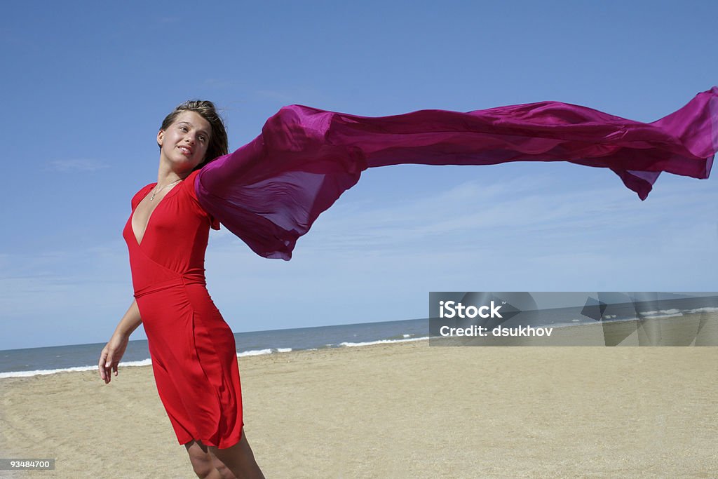 Giovane donna sulla spiaggia con sciarpa svolazzanti rosso - Foto stock royalty-free di Acqua