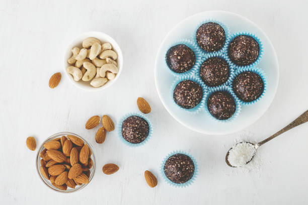 istock Healthy chocolate energy bites with nuts, dates, cocoa powder, coconut flakes on white table. 934855004