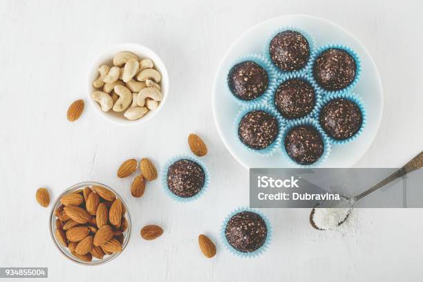 Healthy Chocolate Energy Bites With Nuts Dates Cocoa Powder Coconut Flakes On White Table Stock Photo - Download Image Now