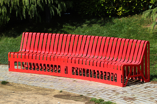 Long red metal bench in a public park