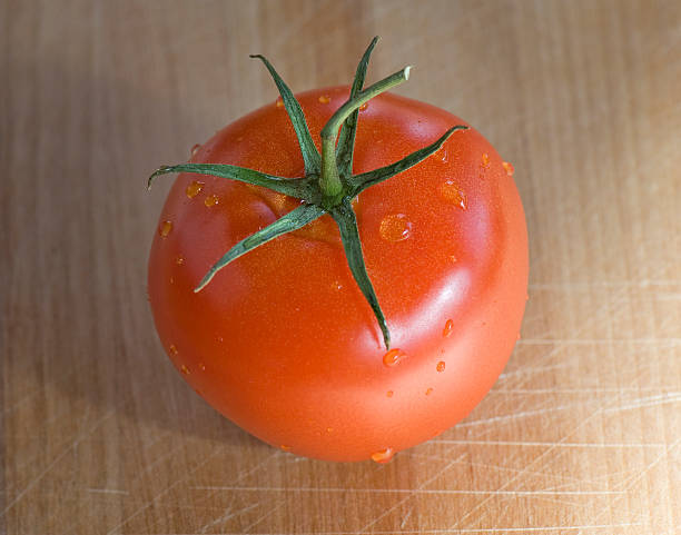 Isolated tomato on wood cutting board stock photo