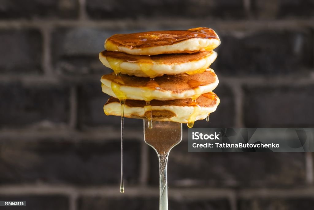 Pancake with liquid honey on brick background. Selective focus. Homemade pancake with liquid sweet honey on brick background. Selective focus. Pancake Stock Photo