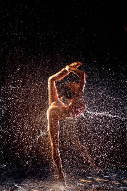 Beautiful girl gymnast in a spray of water