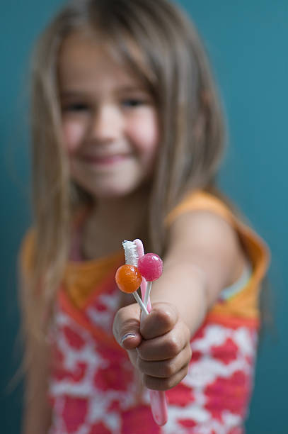 маленькая девочка (5 лет), держит два lollipops и зубная щётка - 4 5 years flash стоковые фото и изображения