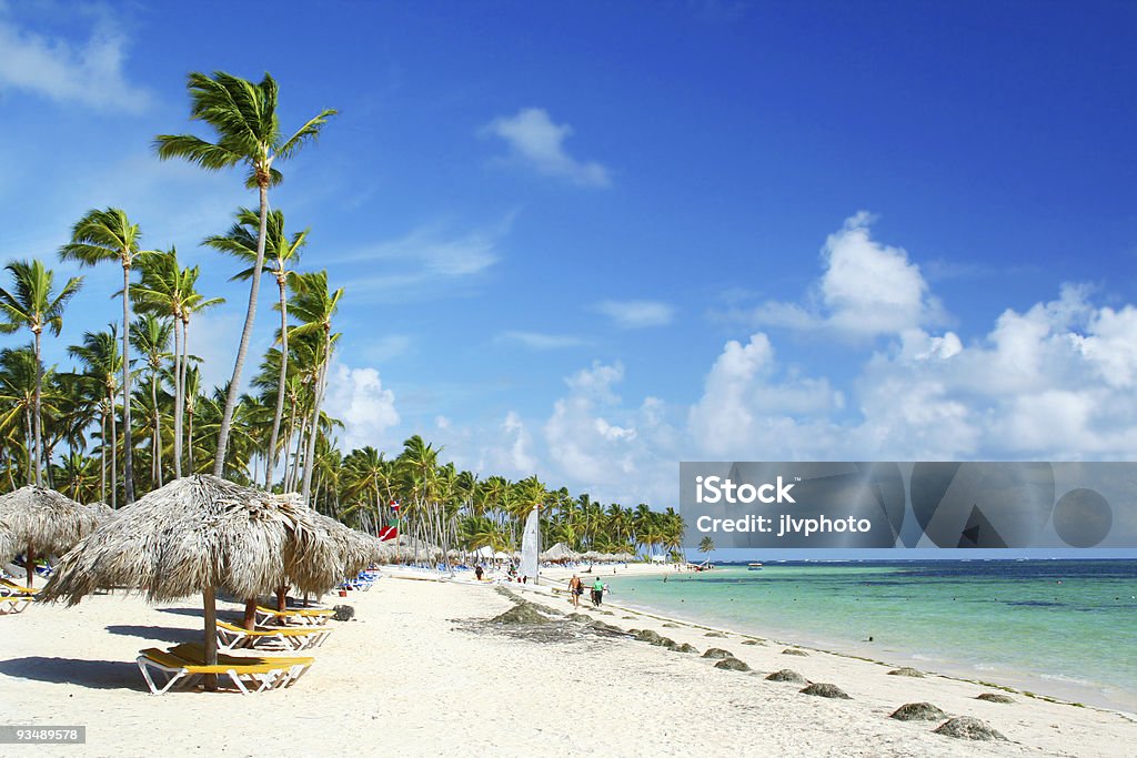 A sunny day at the Caribbean Resort Beach Caribbean resort beach fringed with palm trees and grass umbrellas. Jamaica Stock Photo