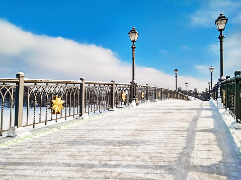 Snowy bridge with lamps at blue sky background at winter daylight time