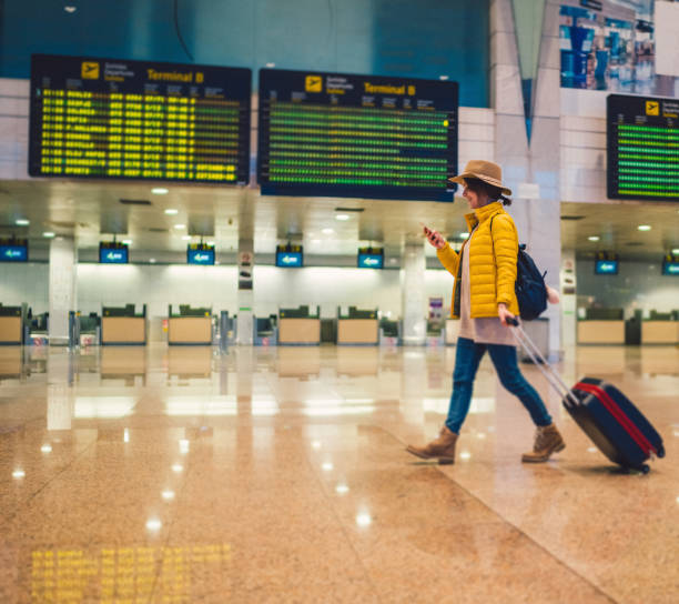 giovane donna che usa lo smartphone al terminal dell'aeroporto - heathrow airport immagine foto e immagini stock