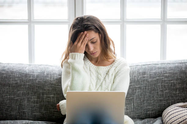 Frustrated woman worried about problem sitting on sofa with laptop Frustrated sad woman feeling tired worried about problem sitting on sofa with laptop, stressed depressed girl troubled with reading bad news online, email notification about debt or negative message disappointment photos stock pictures, royalty-free photos & images