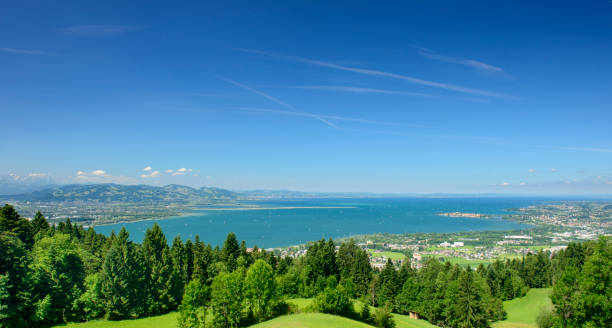 View from the idyllic mountain-village Eichenberg in Vorarlberg in the Austrian alps. There are hills with forest in the foreground and the lake of constance with the German and the Swiss coast in the background.