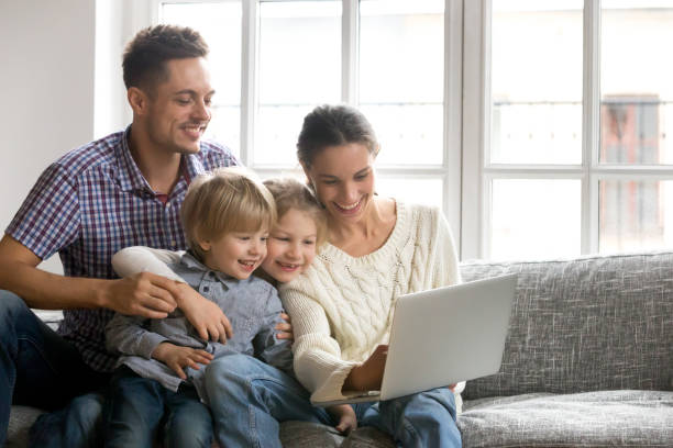 istock Family of four using laptop sitting on sofa at home 934921752