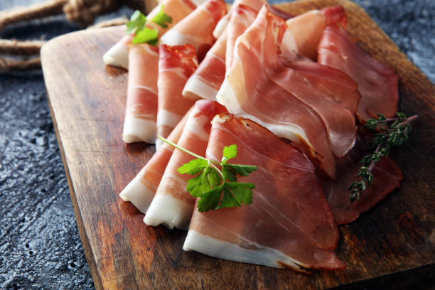 prosciutto crudo o jamon italiano con prezzemolo. prosciutto crudo - crudo foto e immagini stock