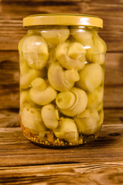 Jar with canned mushrooms on rustic wooden table
