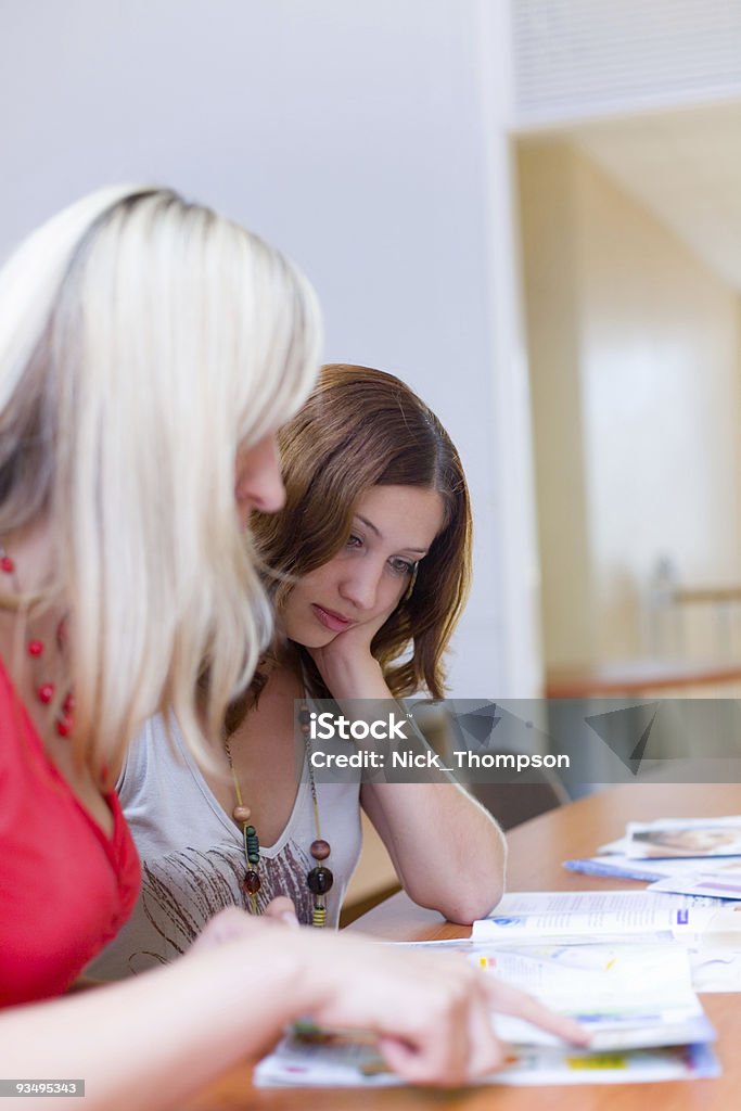 Dos hermosas chicas son mirando a través de una revista - Foto de stock de A la moda libre de derechos