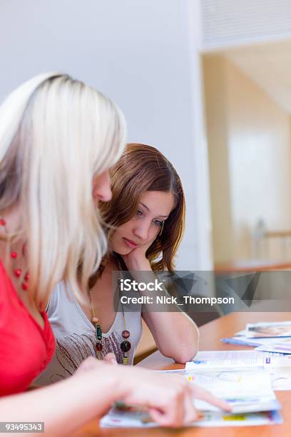 Due Belle Ragazze Guardando Attraverso Una Rivista - Fotografie stock e altre immagini di Abbigliamento - Abbigliamento, Abbigliamento casual, Adulto