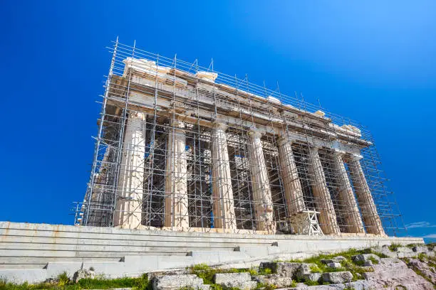 Photo of Restoration work in progress at world heritage ancient Parthenon with machine crane, scaffolding and blue sky background, Athens, Greece