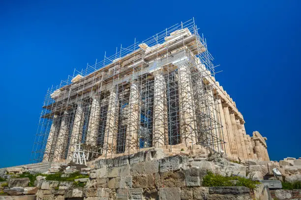 Photo of Restoration work in progress at world heritage ancient Parthenon with machine crane, scaffolding and blue sky background, Athens, Greece