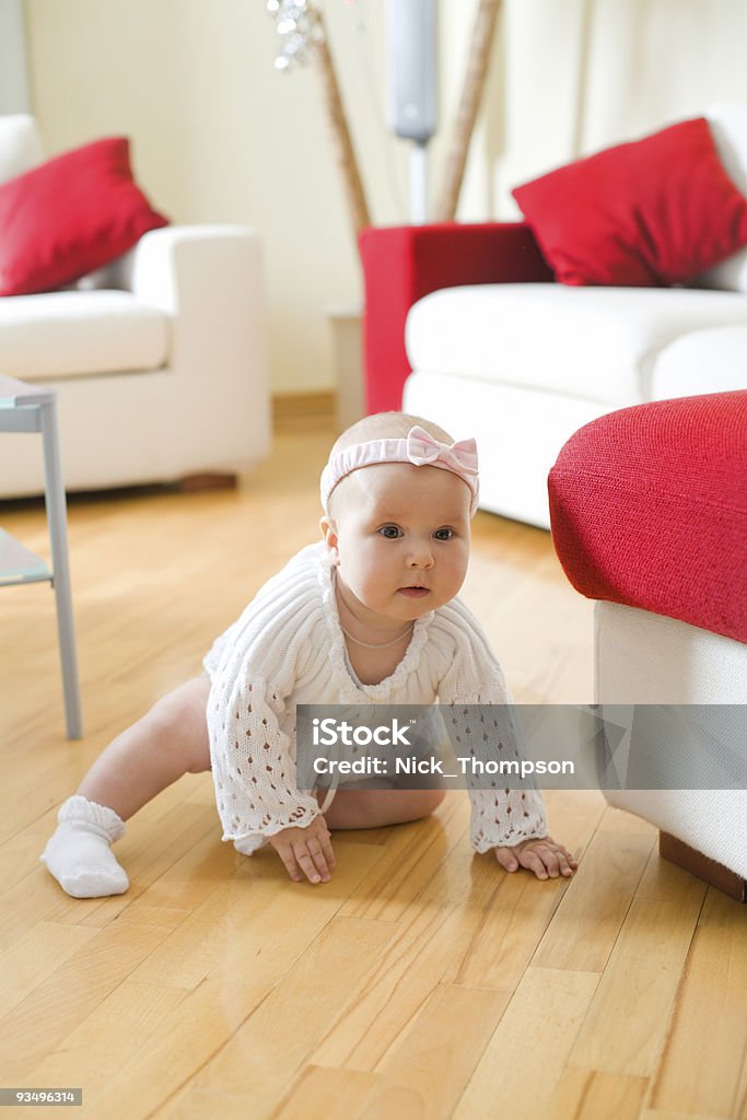 Happy baby girl crawling on a hardwood floor  6-11 Months Stock Photo