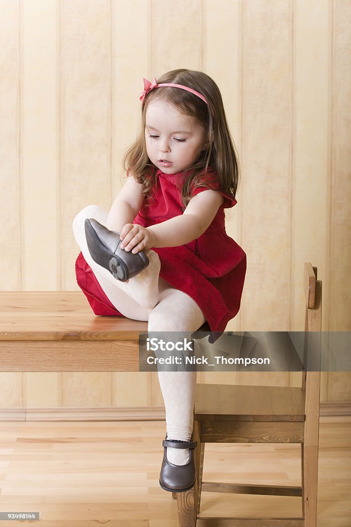 Kleines Mädchen sitzt am Tisch auf einem Schuh - Lizenzfrei Anziehen Stock-Foto