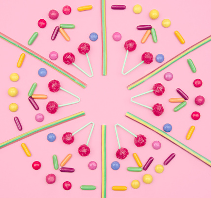 Assorted colored candies on pink background. Flat lay, top view.