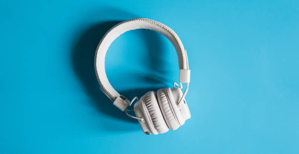 istock Close-up white wireless headphones on a turquoise background top view. 935035374
