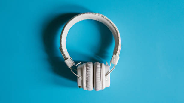 istock Close-up white wireless headphones on a turquoise background top view. 935035404